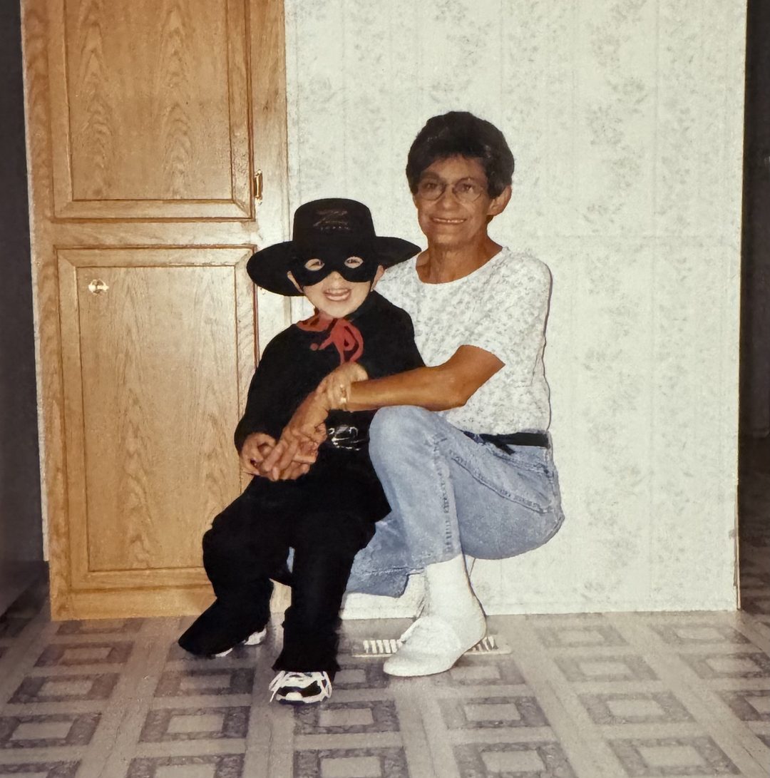 Little John dressed as Zorro, crouched next to his grandmother.